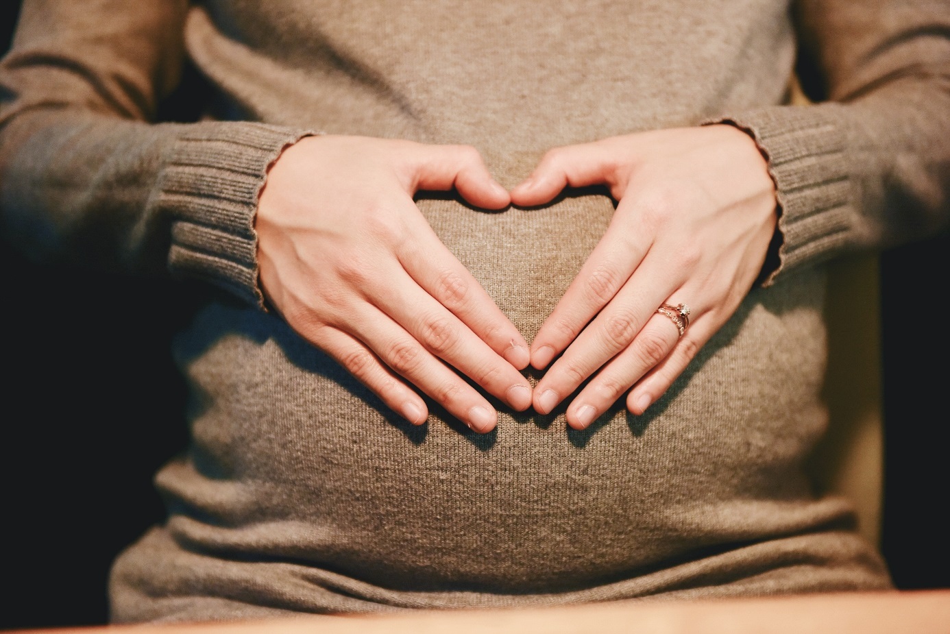Schwangere Frau legt sich die Hände auf den Bauch