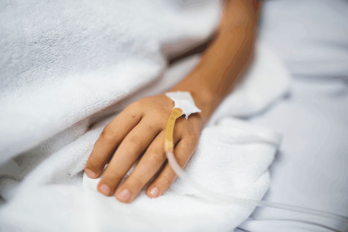Linke Hand im Krankenhausbett mit Injektionsnadel